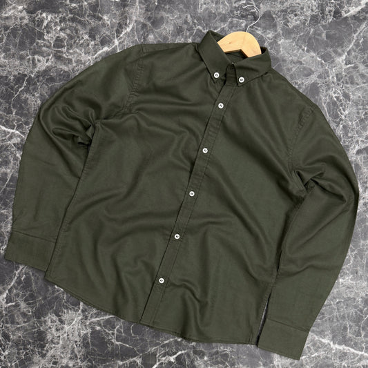 Green shirt on a wooden hanger against a gray marble background